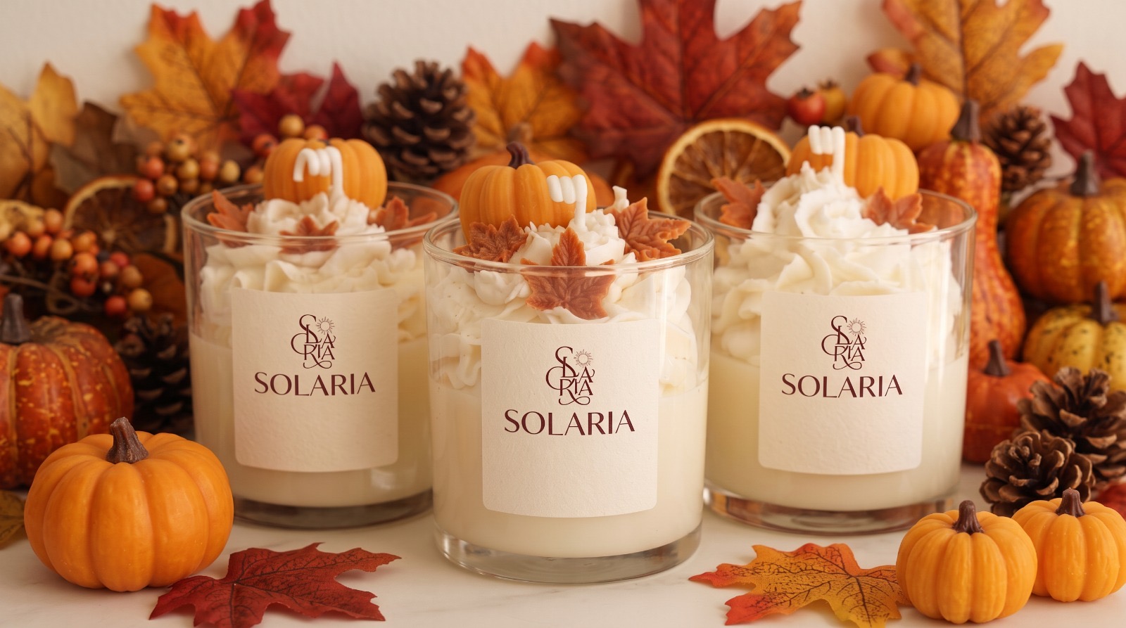 Tres velas Solaria de cera de soja entre hojas de otoño, calabazas y piñas